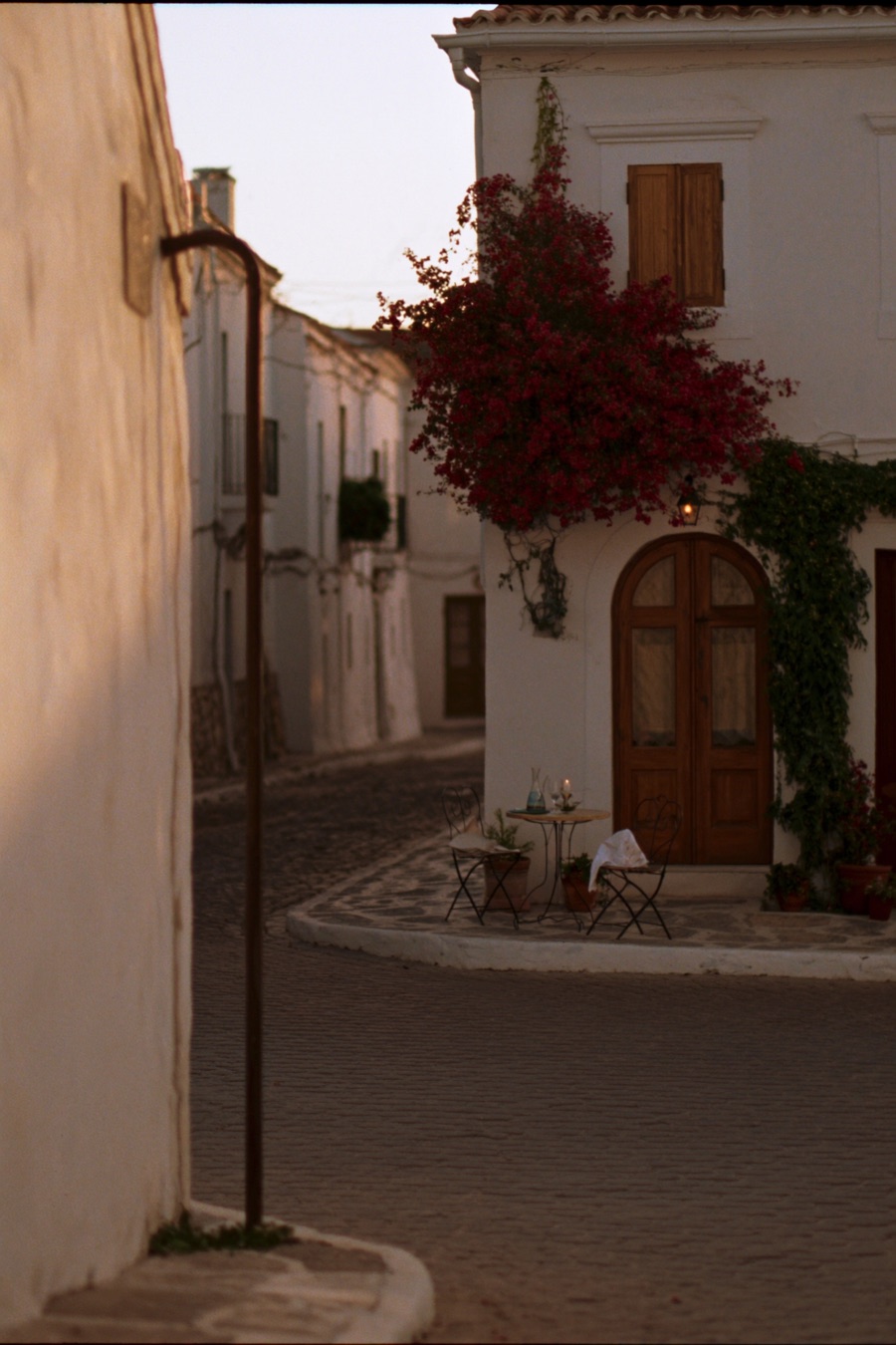 A candlelit table for two on a European village lane at dusk