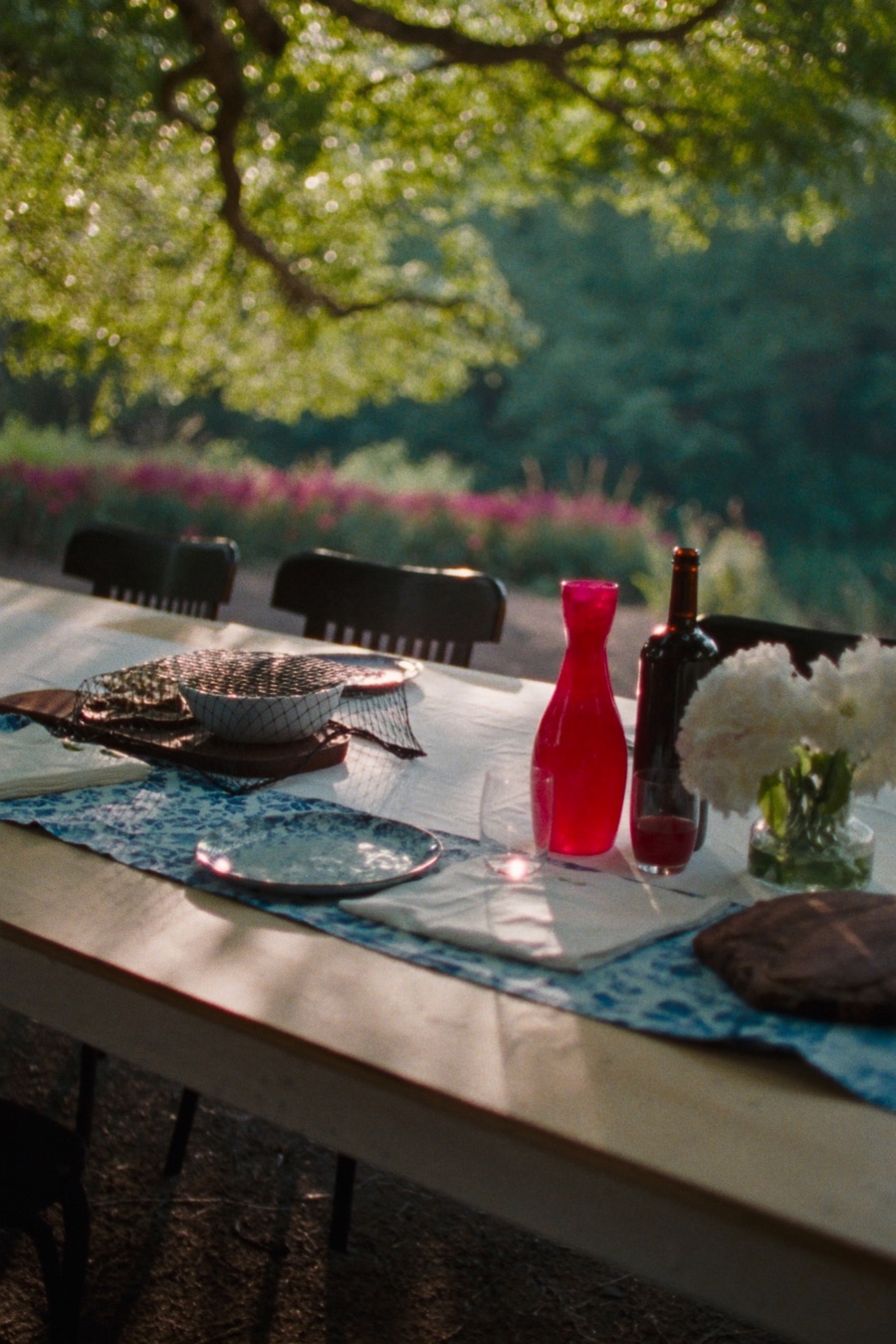 A long table set for a family meal in a garden at golden hour